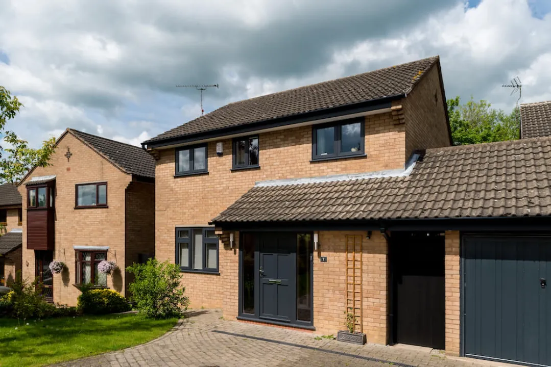 A modern two-story brick home featuring dark grey UPVC windows and a dark grey front entrance door.