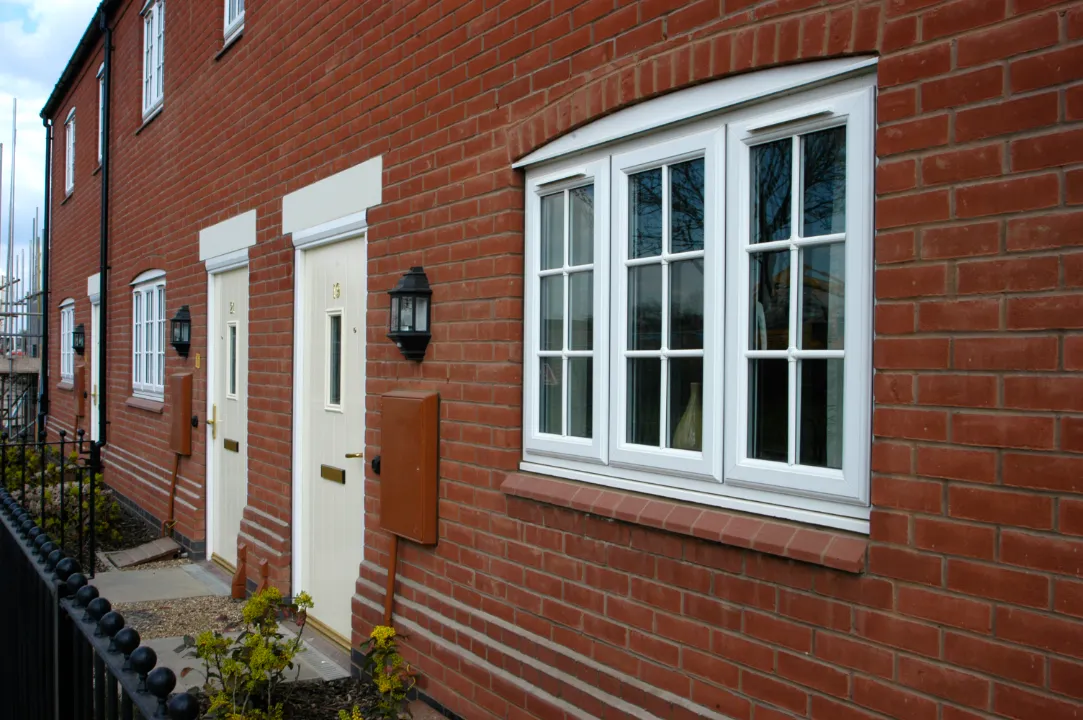 White Georgian-style uPVC windows and entrance doors on a red brick property