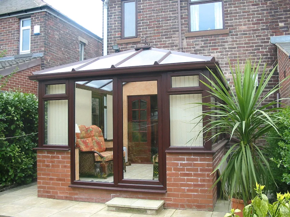 Dark wood-effect conservatory with glass doors built on a brick base attached to a brick house.