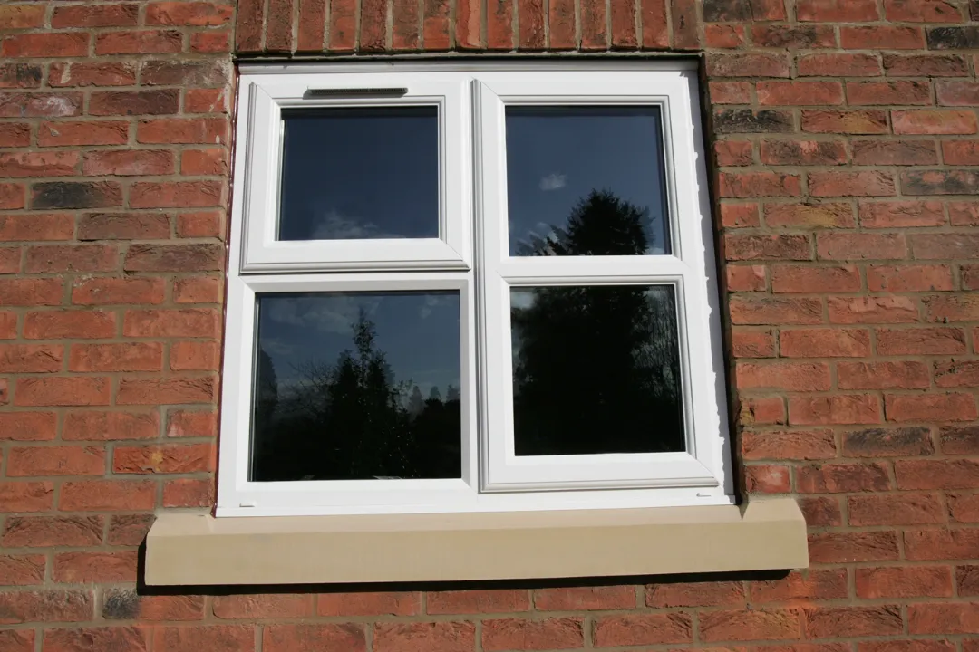 White casement window fitted into a red brick exterior wall