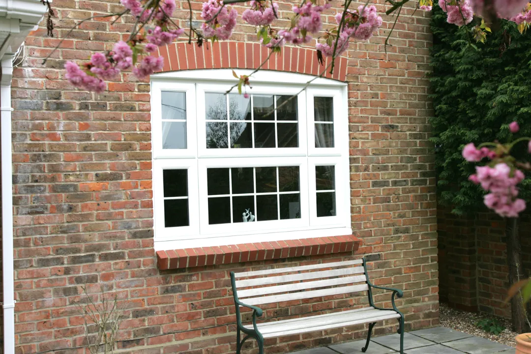 White casement window with glazing bars on a traditional brick home
