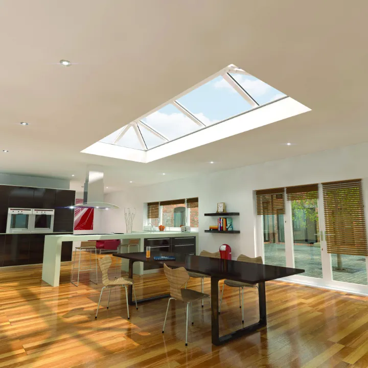 Bright, modern open-plan kitchen and dining area featuring a large rectangular roof lantern in the center of the ceiling.